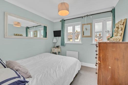 a bedroom with a bed and two windows at Stylish 3 bedroom townhouse for 5 guests, set in the medieval grid with off street parking in Bury Saint Edmunds