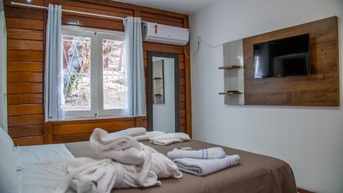a bedroom with towels on a bed with a tv at Verde Mar Pipa Beach in Pipa