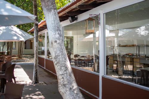 a restaurant with glass windows and tables and chairs at Verde Mar Pipa Beach in Pipa