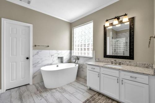 a bathroom with a tub and a sink and a mirror at Taupewood Pl in The Woodlands