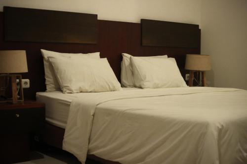 a large white bed with white sheets and pillows at Hotel Graha Kinasih Kotabaru in Yogyakarta