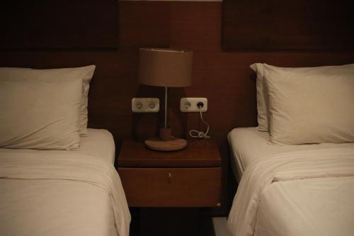 a bedroom with two beds and a lamp on a night stand at Hotel Graha Kinasih Kotabaru in Yogyakarta