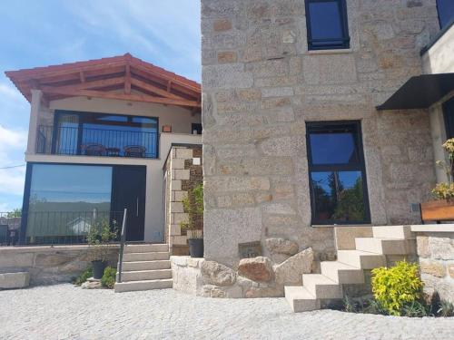 uma casa de pedra com escadas e uma varanda em Casinhas da eira caramulo turismo rural em Arca