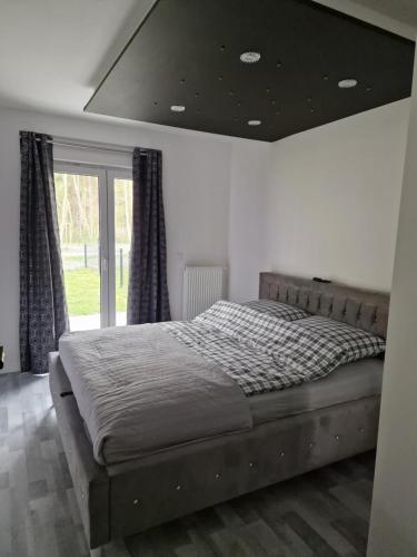 a large bed in a bedroom with a large window at Apartament Plażowa in Międzywodzie