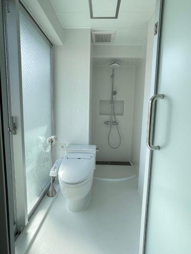 a white bathroom with a toilet and a shower at Hotel Apreton in Tokyo