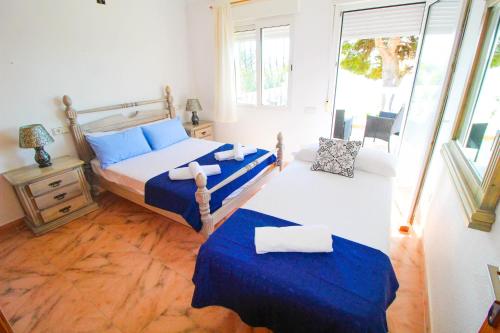 um quarto com uma cama com lençóis azuis e uma janela em Great villa, Sea views, 20 secs walk to the beach, BBQ, 9 people, 5 mins car from Alicante city center, sailing club 3 mins walk em Alicante