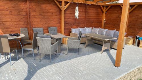 a patio with chairs and tables and a wooden wall at Ubytování U Truhlářů Šaldorf in Nový Šaldorf