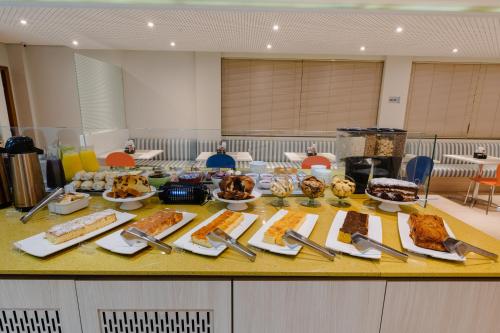 a table filled with different types of bread and pastries at Hotel Caiuá Lago Umuarama in Umuarama