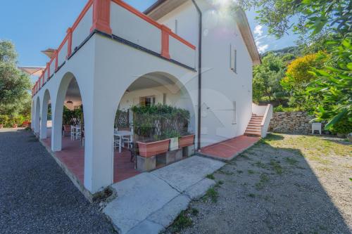 a white building with a patio with tables and chairs at La Palazzina nel Verde - Goelba in Campo nell'Elba