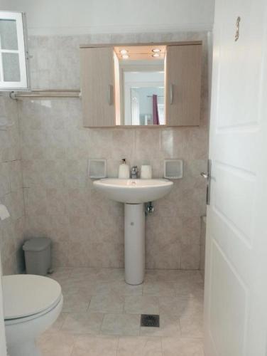 a bathroom with a sink and a toilet and a mirror at Levante Breeze in Xirokástellon