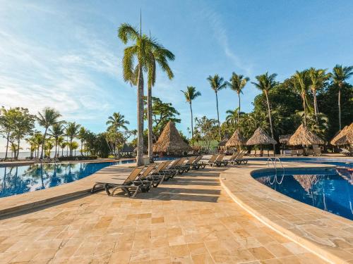 a resort swimming pool with chairs and palm trees at Barceló Tambor - All Inclusive in Tambor
