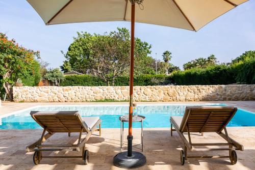 duas cadeiras e um guarda-sol ao lado de uma piscina em ONLY FAMILIES Villa and Guest House with Private Pool em Chiclana de la Frontera