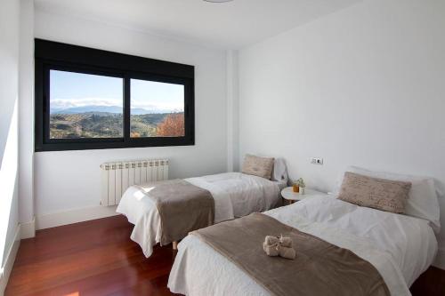 a bedroom with two beds and a large window at Relajante villa, deportes, piscina y vistas a S Nevada in Huétor Santillán