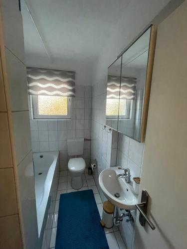 ein Badezimmer mit einem Waschbecken, einem WC und einem Spiegel in der Unterkunft Sana Ferienwohnung in Oberhausen