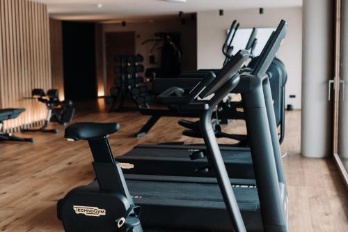 a gym with several treadmills and exercise bikes at Familienhotel Familiamus in Maranza