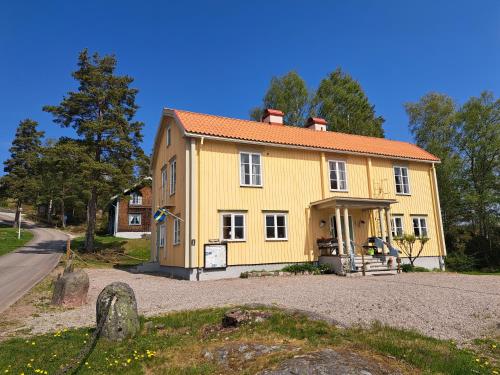 a yellow house with an orange roof on a road at Vandrarhemmet Gammelgården in Bengtsfors