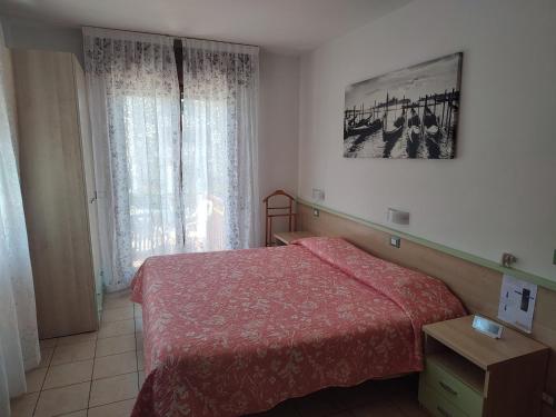 una camera con letto rosso e finestra di Bar Moro 1963 a Cavallino-Treporti