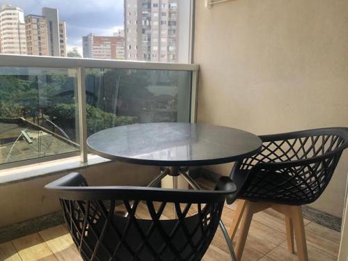 a table and two chairs in a room with a window at Apart-Hotel de Luxo em Lourdes in Belo Horizonte