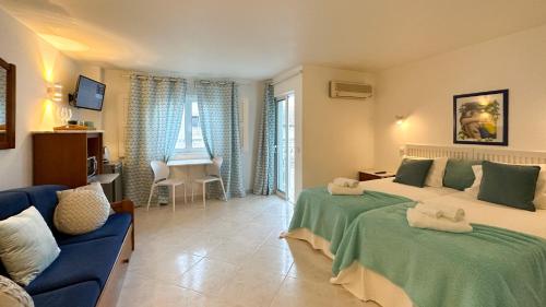 a bedroom with two beds and a blue couch at Sofeelings, Quarto Mar Piso 2, Baixa de Albufeira in Albufeira