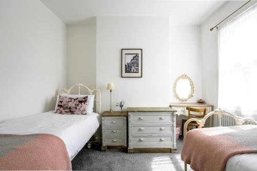 a bedroom with two beds and a dresser and a mirror at Chester Stays - Lovely 2 bedroom house in the heart of Chester in Chester