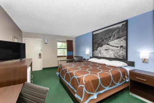 a hotel room with a bed and a flat screen tv at Super 8 by Wyndham Malvern in Malvern