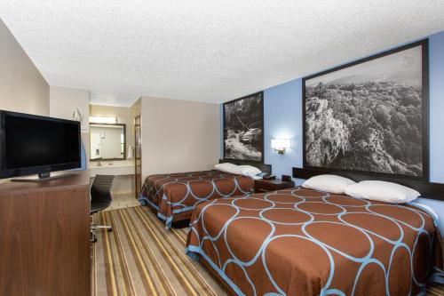 a hotel room with two beds and a flat screen tv at Super 8 by Wyndham Malvern in Malvern