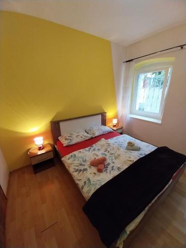 a bedroom with a bed and a window and two lamps at Apartmani Jadran in Mali Lošinj
