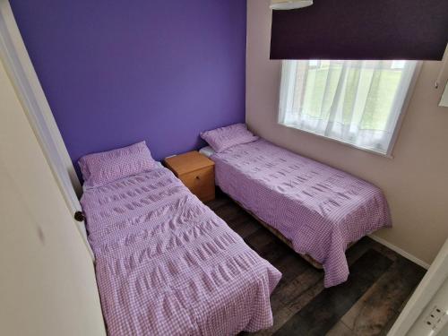 Duas camas num pequeno quarto com paredes roxas em Rosie's Place em Great Yarmouth
