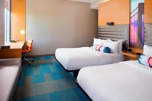 a hotel room with two beds and a desk at Aloft Philadelphia Airport in Philadelphia