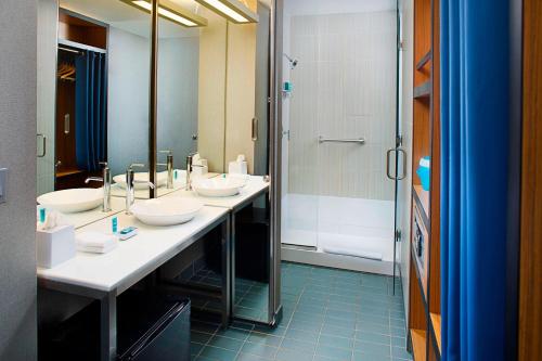 a bathroom with three sinks and a shower at Aloft Philadelphia Airport in Philadelphia