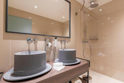 uma casa de banho com um espelho grande e um chuveiro em Marmont Hotel em Genebra