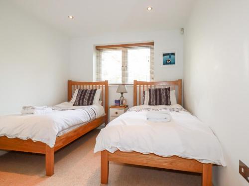 2 camas individuais num quarto com paredes brancas em Pebbles em Torpoint