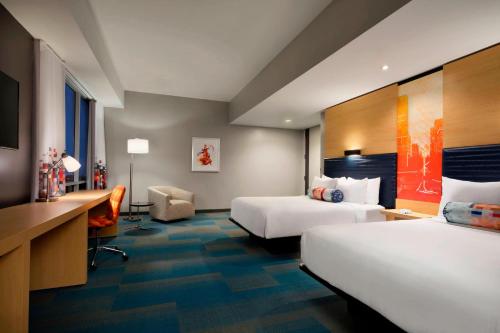 a hotel room with two beds and a desk at Aloft Columbia Downtown in Columbia
