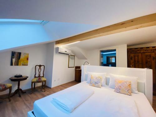 テルメーノにあるHotel Garni Vinea Montisのベッドルーム(大きな白いベッド1台、椅子付)