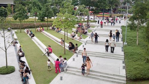 a group of people walking and sitting in a park at Avant Apartments at The Fort in Manila