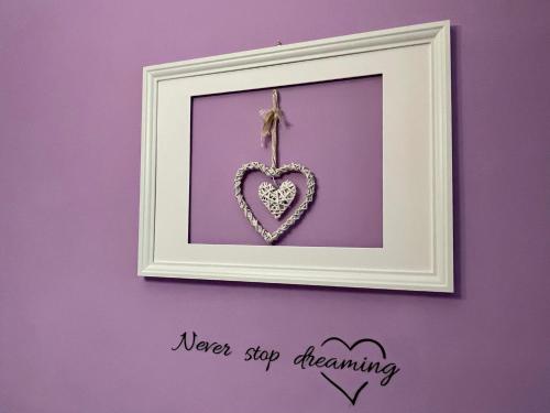 a picture of a heart in a frame on a purple wall at Appartamento Chagall in Asti