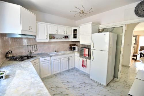 eine Küche mit weißen Schränken und einem weißen Kühlschrank in der Unterkunft VILLA KIKA ZARZIS, LOCATION CHAMBRES D'HÔTES en TUNISIE in Zarzis