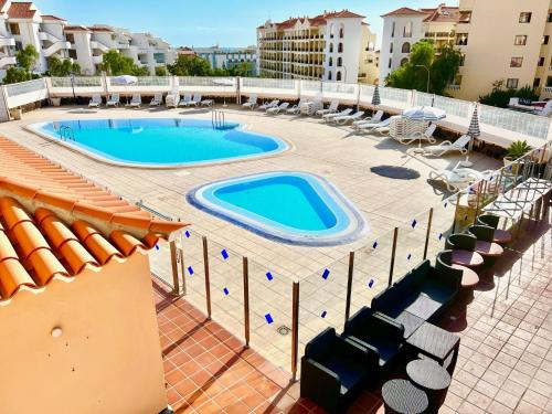 uma grande piscina com cadeiras e um edifício em !!! Relaxing View, The Heights Apartment With Terrace and Heated Pools, Los Cristianos em Los Cristianos