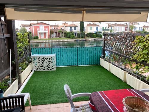 un balcón con un patio verde con piscina en Appartement rue de l'amarrage à PORT GRIMAUD avec Terrasse vue canaux et garage, en Grimaud