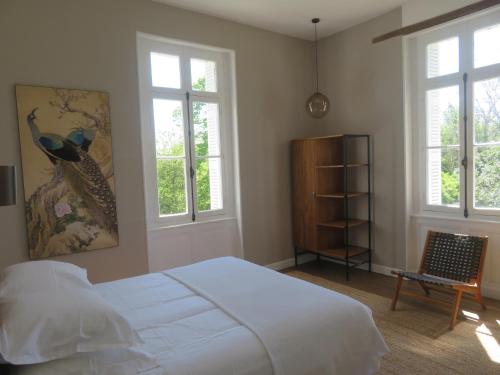 a bedroom with a bed and two windows and a chair at Villa Paignon in Montbron