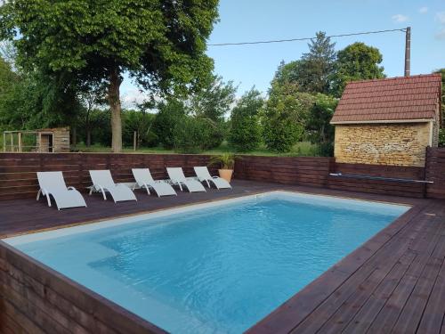 une piscine avec des chaises longues sur une terrasse en bois dans l'établissement Les gîtes de Louise, à Archignac