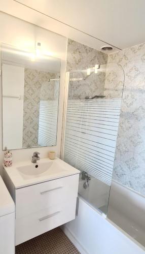 une salle de bain avec un lavabo, une baignoire et un miroir dans l'établissement Résidence Katikias - vue mer, à Bandol