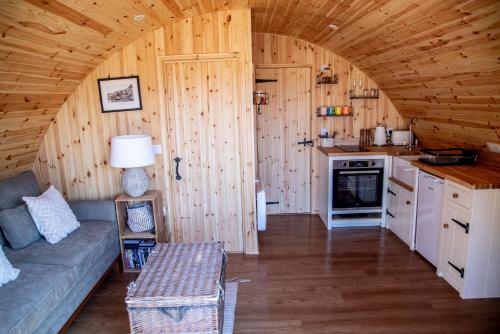 a living room with a couch and a kitchen in a cabin at Barnhorn Glamping in Hooe