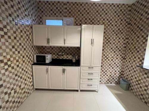 a kitchen with white cabinets and a microwave at روعة بيتك306 in Riyadh