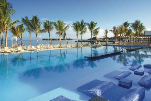 a large swimming pool with chairs and palm trees at Riu Reggae - Adults Only - All Inclusive in Montego Bay