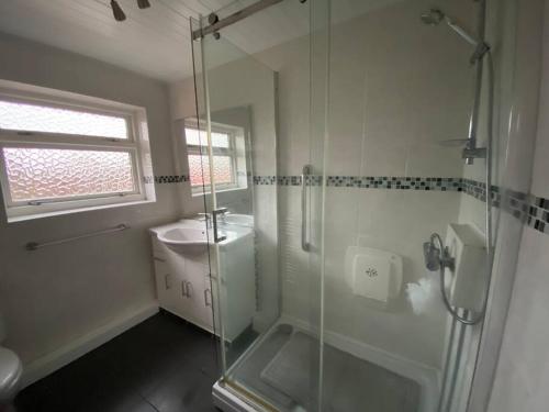a bathroom with a glass shower and a sink at Quiet secluded two bedroom bungalow with parking in Cleveleys