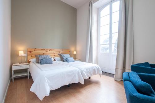 a bedroom with a white bed and a blue chair at Traditional Triana House with 9 en-suite Bedrooms in Las Palmas de Gran Canaria