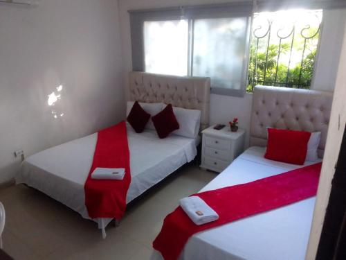 two beds in a bedroom with red and white sheets at buenavista class in Barranquilla