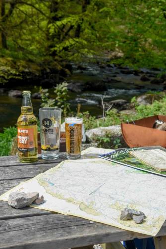 a wooden table with a map and two glasses of beer at Badgers Holt House in Plymouth