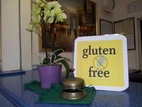 a sign for a gluten free sign next to a plant at Hotel Rosa Meublé in Porto San Giorgio